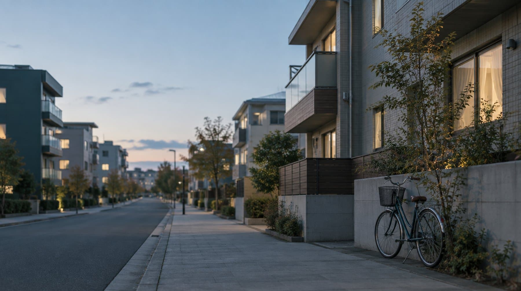夕暮れの住宅街、低い集合住宅の並ぶ通りと壁ぎわの自転車